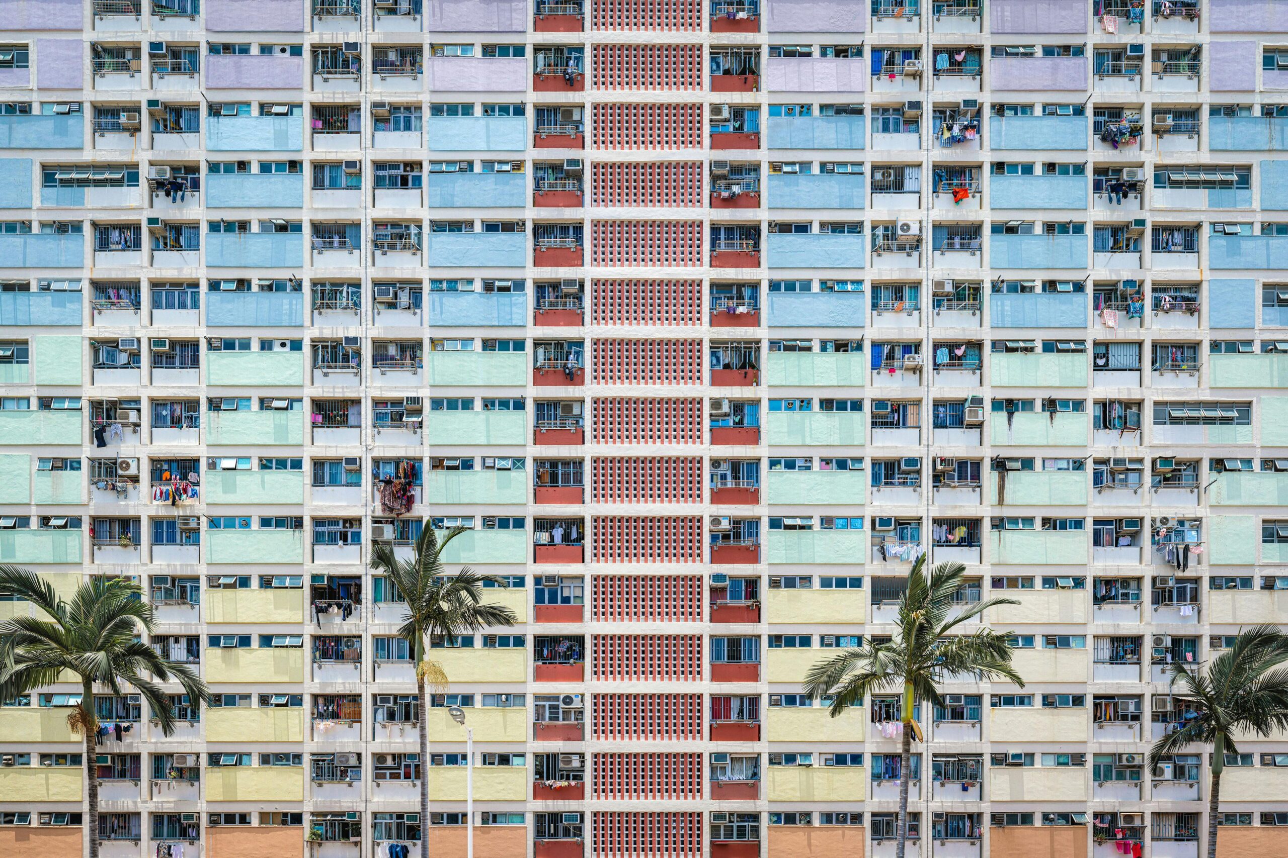 Vibrant facade of an apartment building in Hong Kong with palm trees in the foreground.